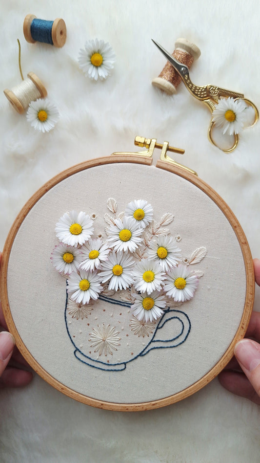 Brodons ensemble une tasse et des pâquerettes